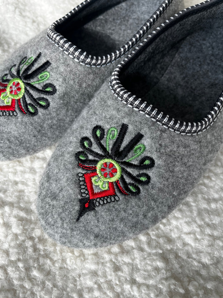 Gray slippers with decorative floral patterns on a textured surface
