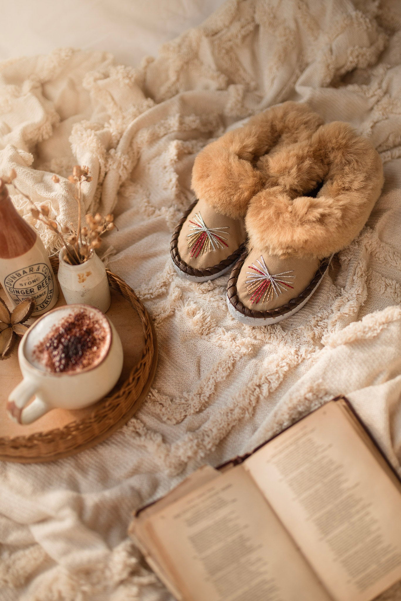 Beige slippers on a soft blanket with a cup of coffee and book nearby