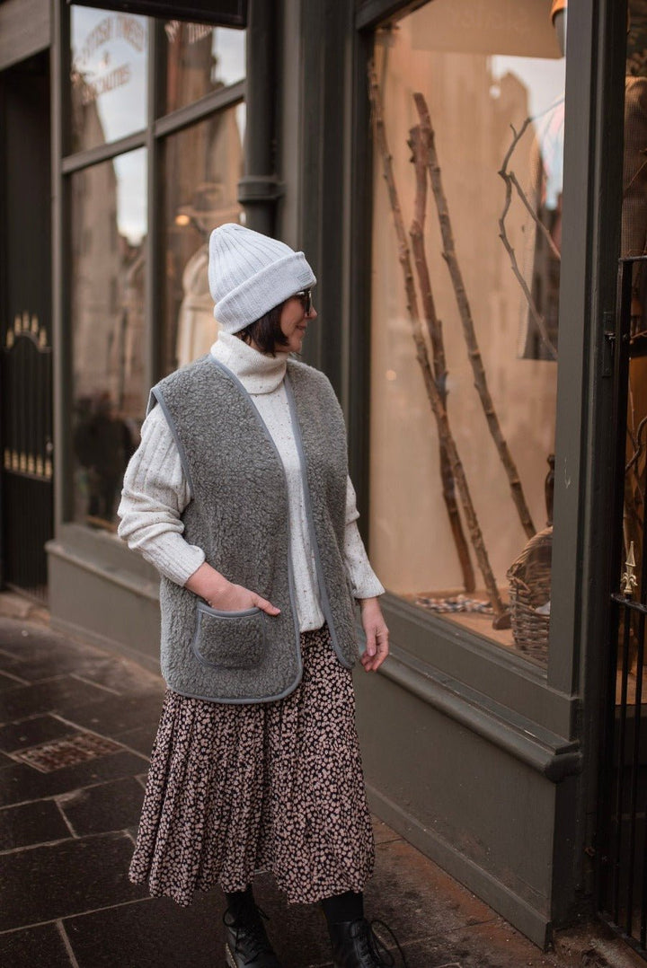 Front view of a woman wearing a grey wool gilet with two large pockets