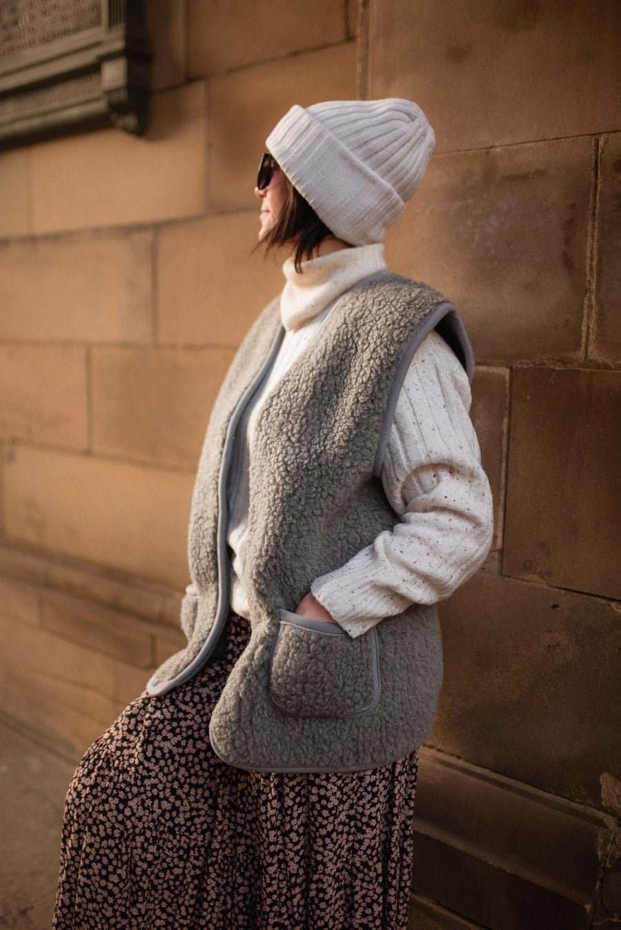 Woman wearing a grey wool gilet with front pockets and fleece edging